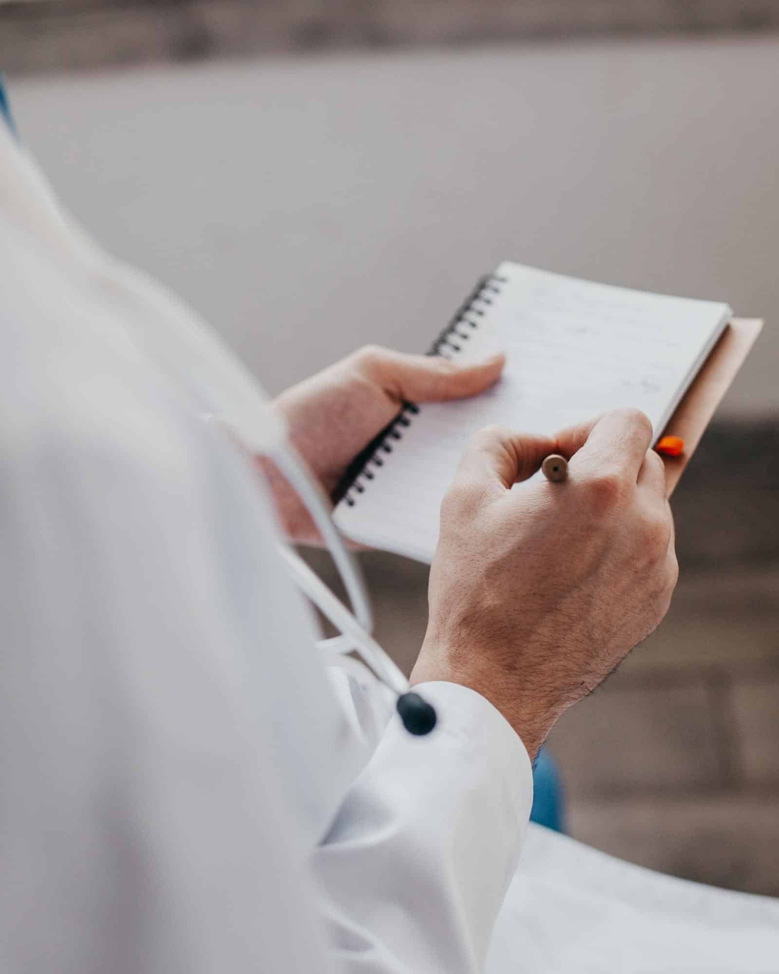 man in white coat writing notes