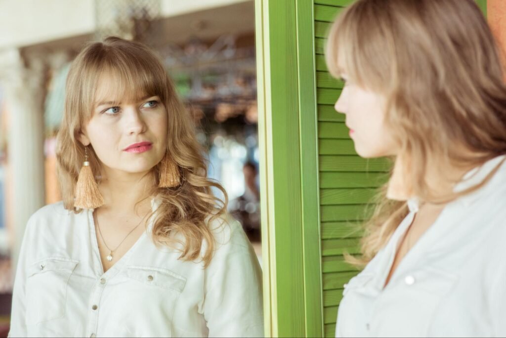 woman looking at herself in a mirror, representing the curiosity behind the question  of aesthetic treatment costs in Weslaco, TX