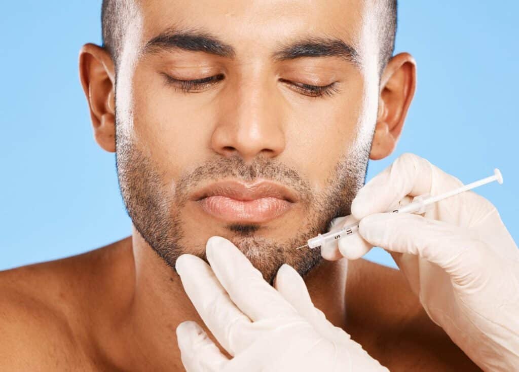 Man receiving a facial injection from a medical provider in a clinical setting, representing the desire to book Botox appointment Weslaco TX