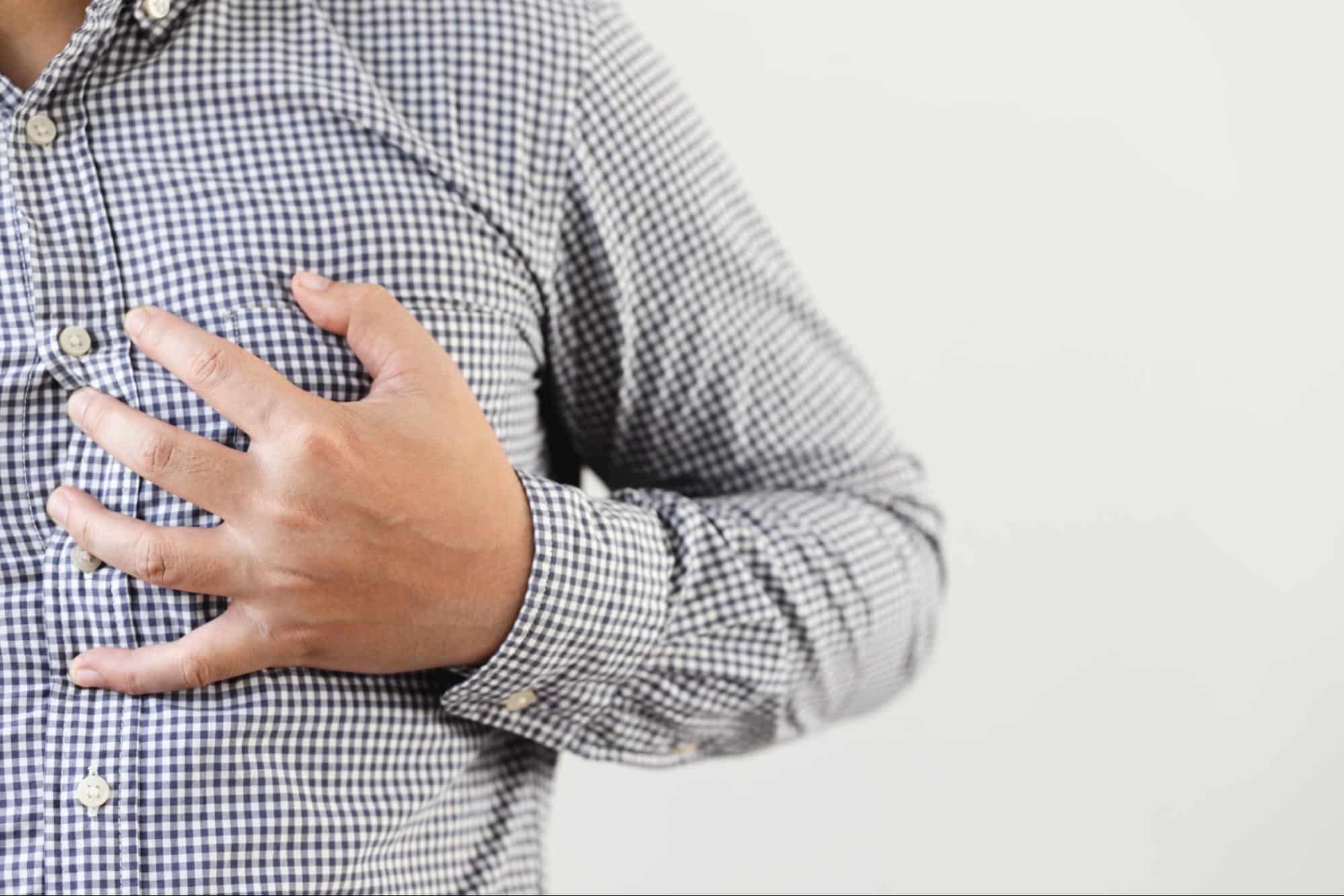 Man holding his chest in pain, highlighting symptoms that require emergency care rather than a late night clinic in Weslaco, TX.