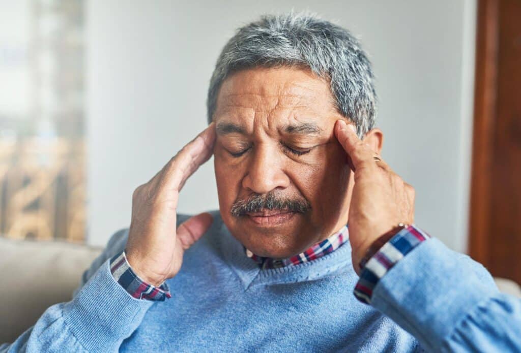 Man holding his temples in discomfort, representing symptoms treated at an after hours clinic Weslaco TX like headaches or illness 