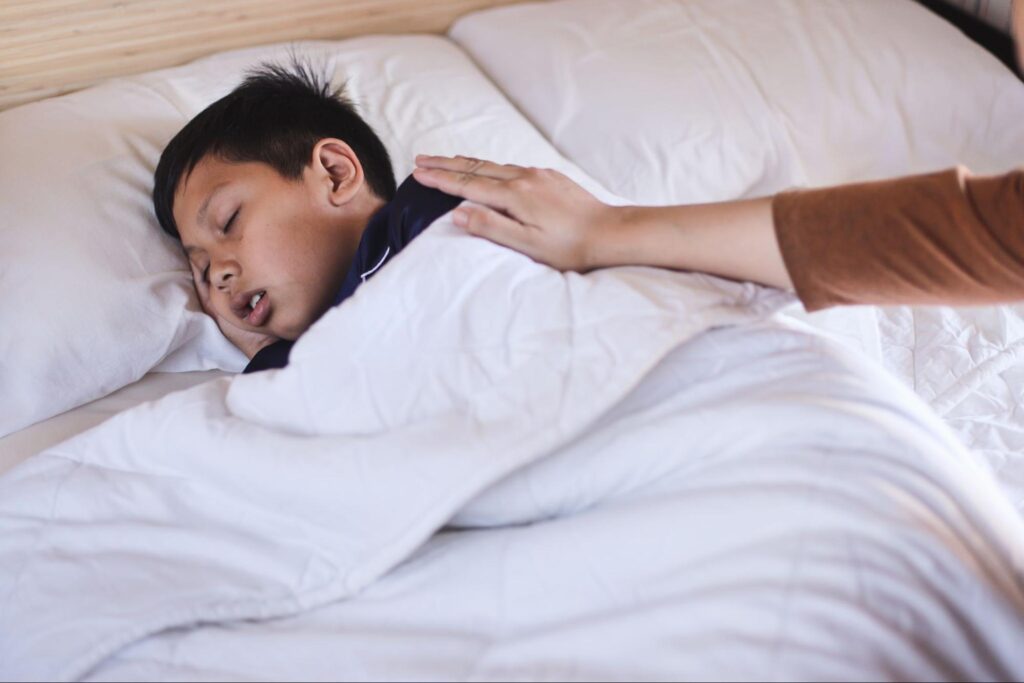 Child resting in bed with a fever while a parent checks on them, a situation where families search for an after hours clinic open now in Weslaco, TX.