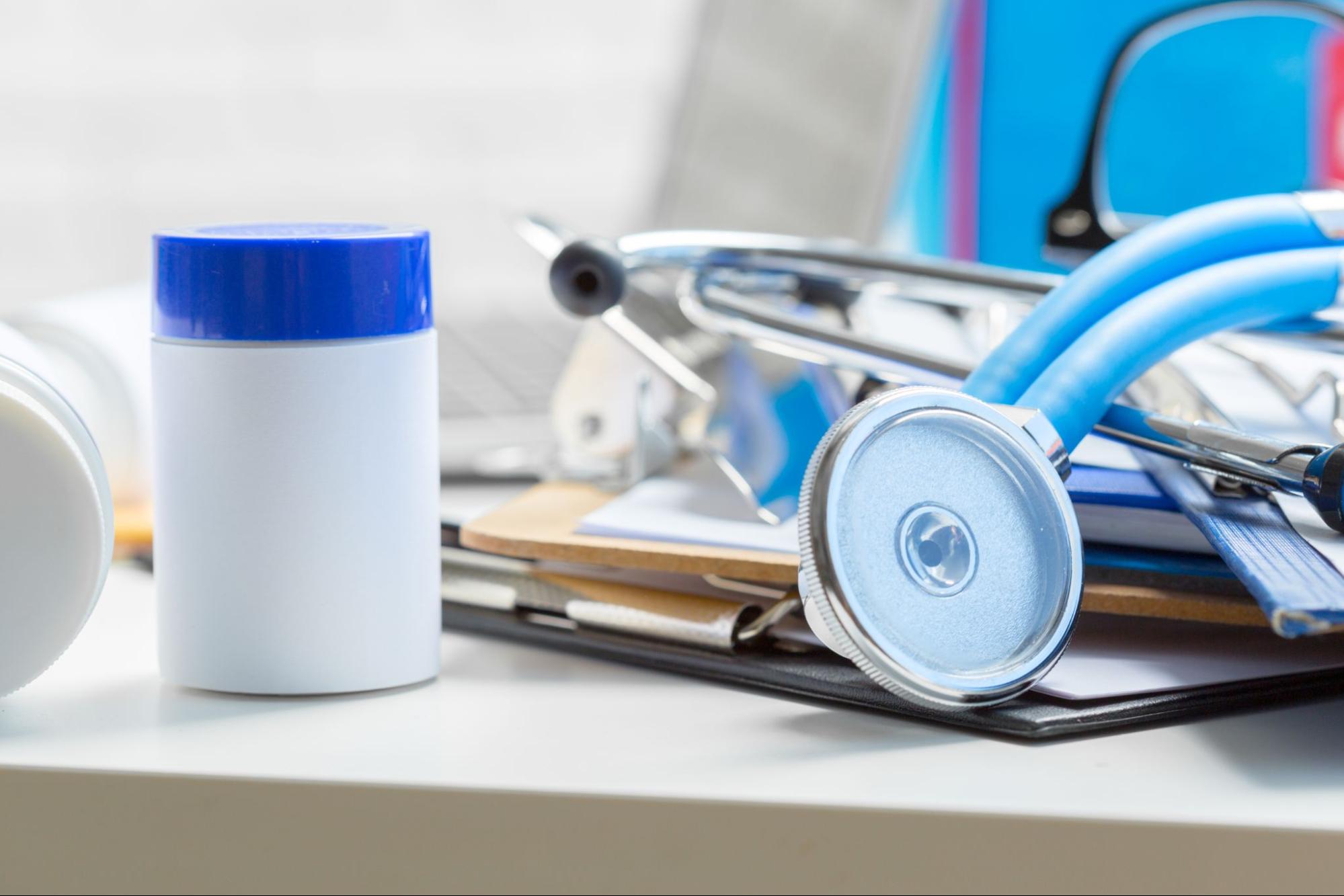 Stethoscope on medical forms beside pill bottles