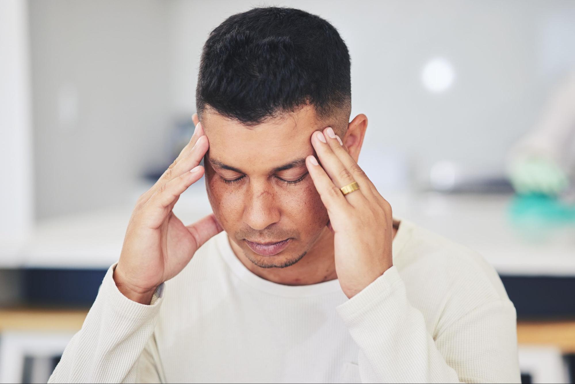 Man holding his temples with eyes closed, showing discomfort and the need for headache relief.