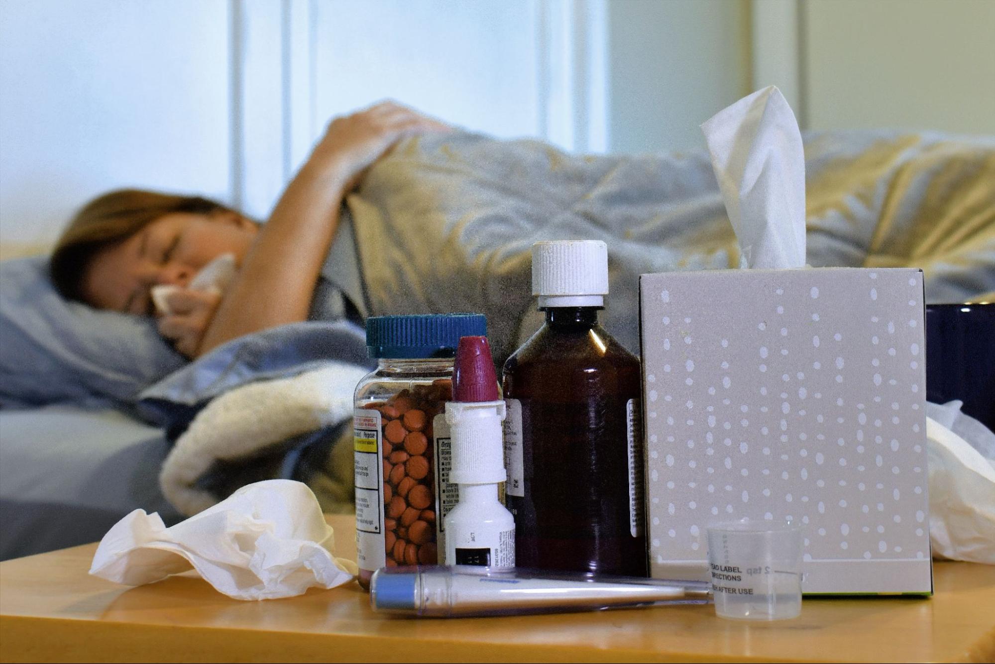 Sick woman resting in bed with tissues and medicine nearby, reflecting visits to a clinic open after hours in Weslaco, TX.