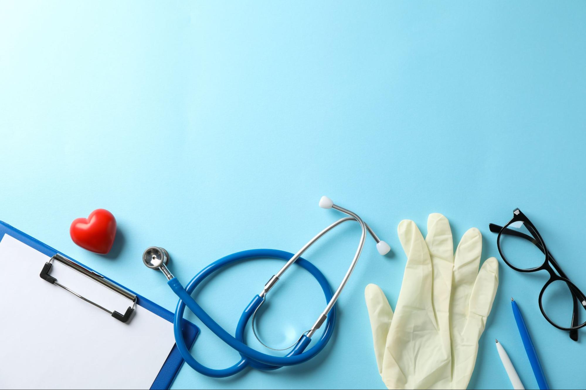 Stethoscope, gloves, and clipboard on blue background, tools used at an after hours medical clinic in Weslaco TX