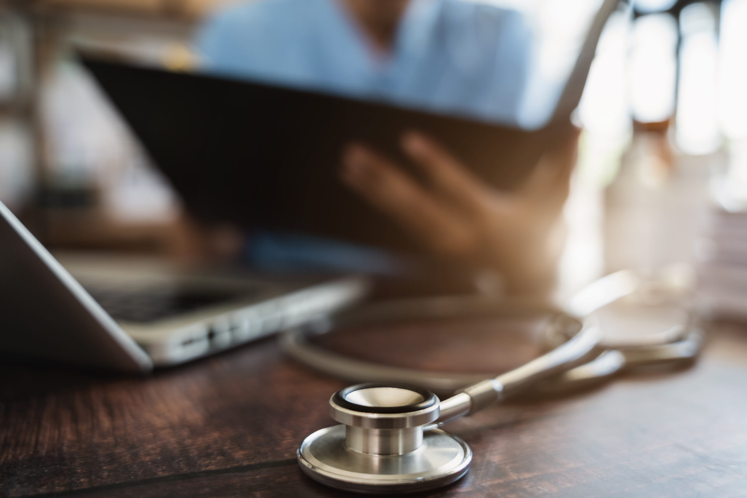 tablet and stethoscope, with primary care provider in the background