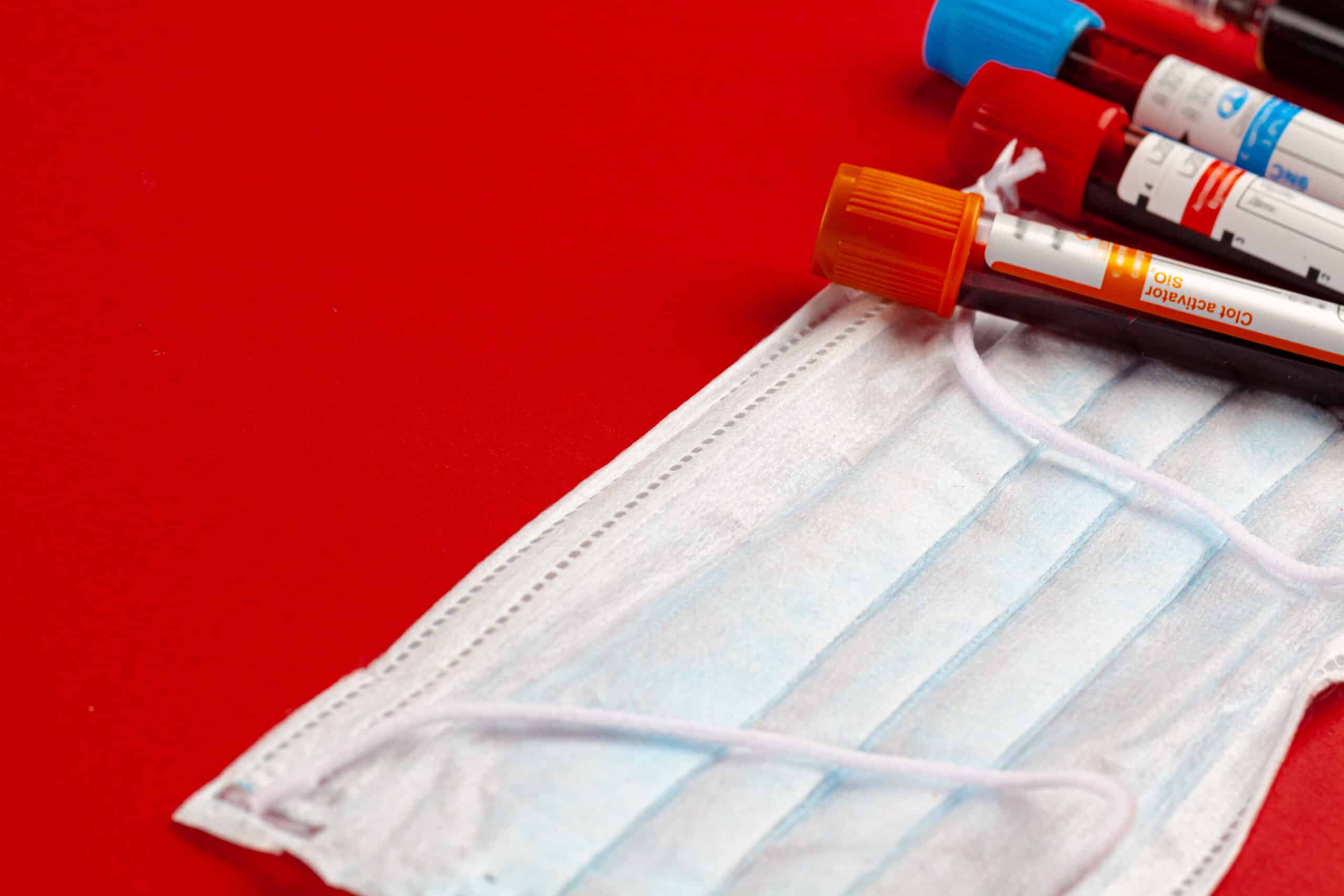 blood samples and face mask on red background
