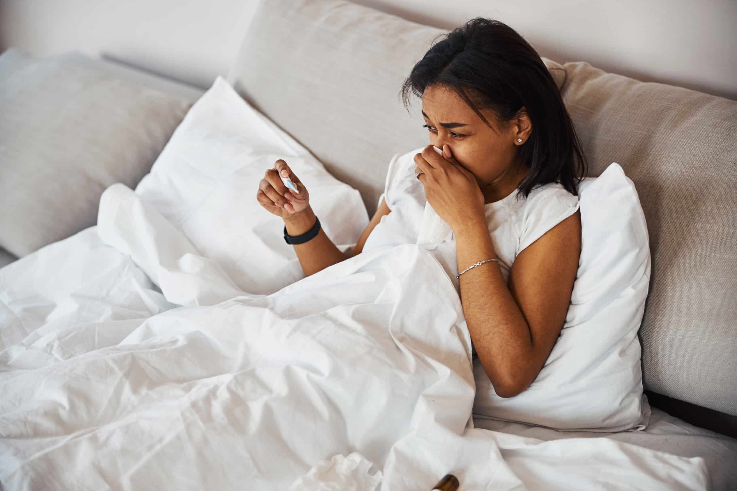 woman checks temperature while sick 